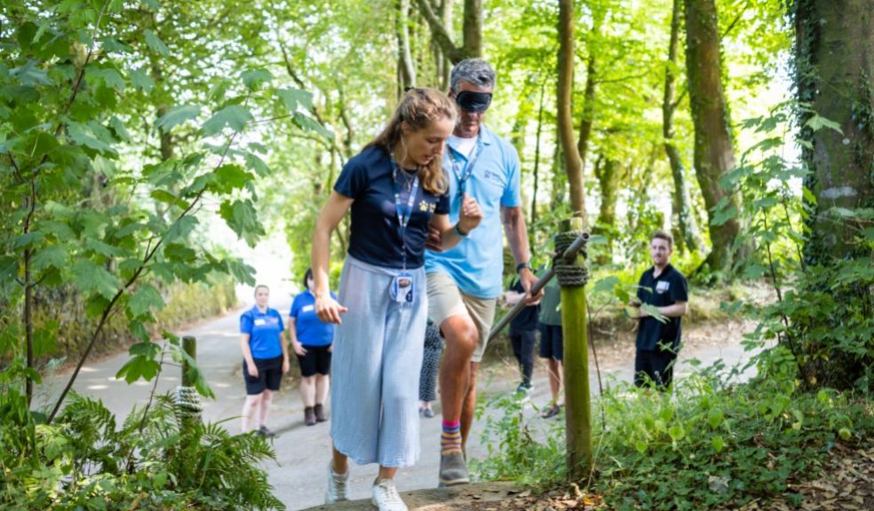 Two staff members from Guide Dogs demonstrate how to guide someone up a set of steps. They are outdo