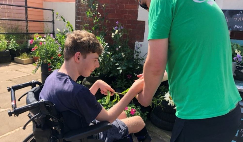 charity worker helping young boy in wheelchair 