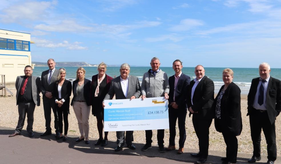Group of people holding a large cheque on a beach