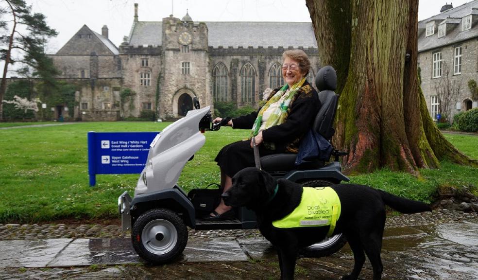Friends of Dartington committee member Helen Robertson with Oscar on all terrain mobility scooter in Dartington Hall courtyard.