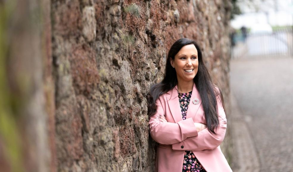 Solicitor in pink jacket leaning against a wall