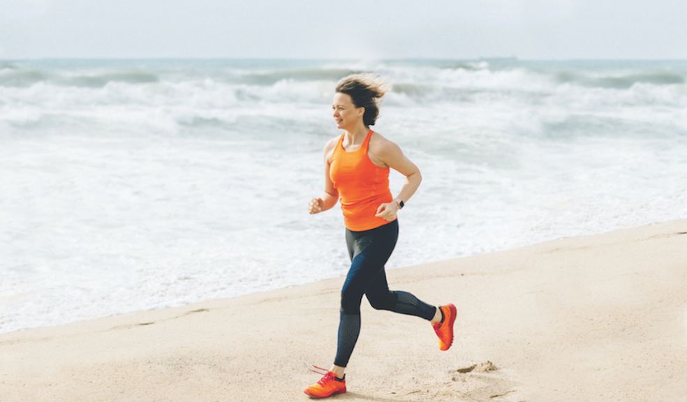 Woman running along a beach close to the shoreline