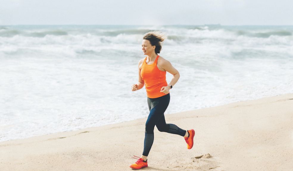 Woman running along a beach close to the shoreline