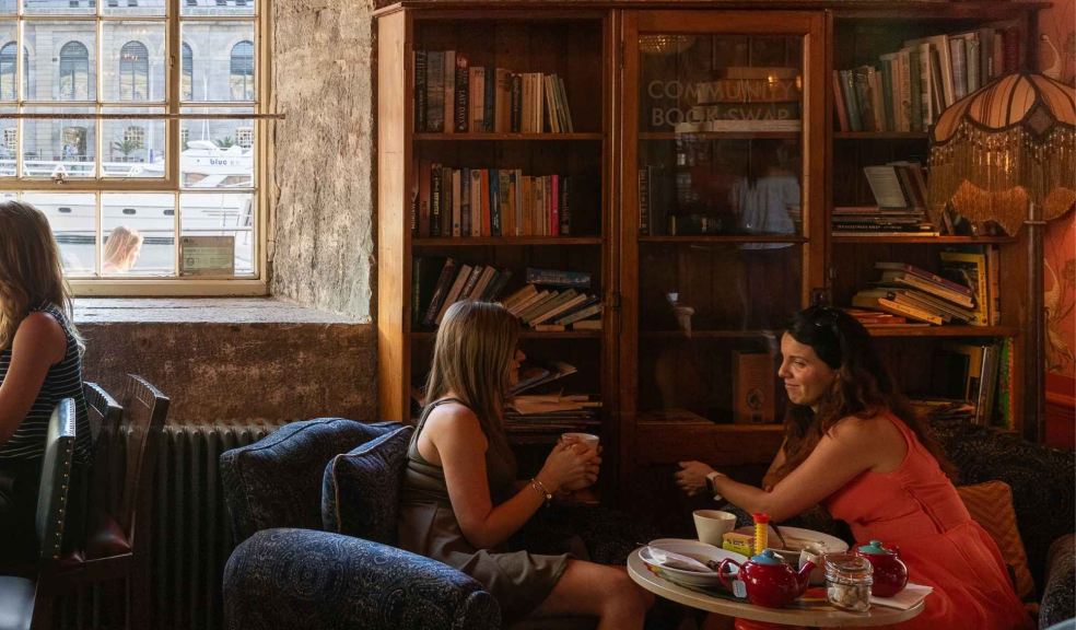 A photograph of people at Royal William Yard with a bookcase behind them