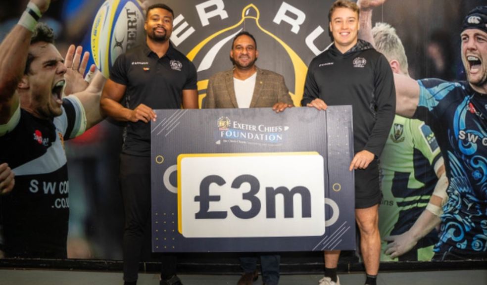 Celebrity Chef Michael Caines, with two Exeter Chiefs rugby players holding  a £3 million board 