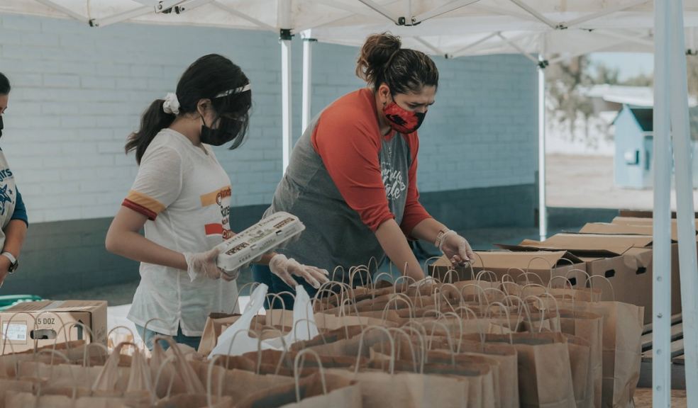 Two women in masks packing food bags