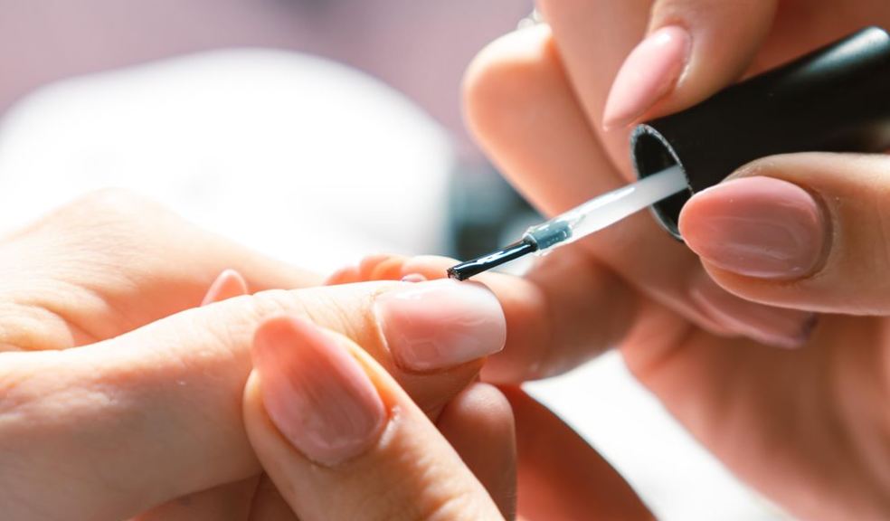 Woman applying nail polish at nail salon