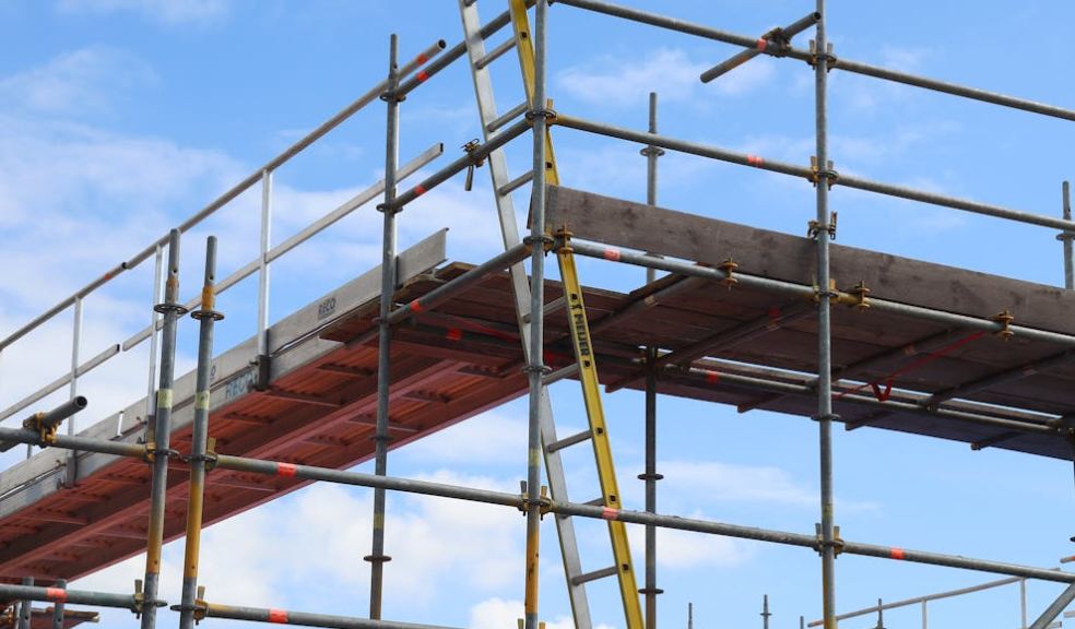 A UK tradesperson working at height with full safety equipment and scaffolding