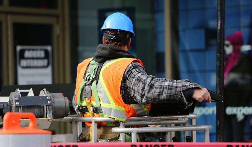 Construction worker on a UK building site wearing a hard hat and high visibility jacket