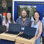 Staff standing with new refurbished laptops for pupils