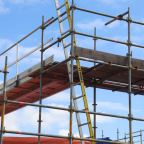 A UK tradesperson working at height with full safety equipment and scaffolding