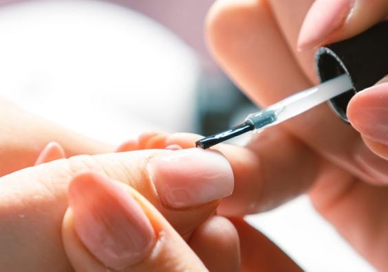 Woman applying nail polish at nail salon