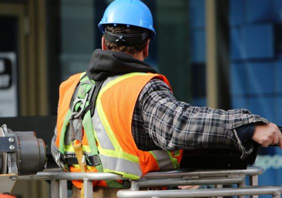 Construction worker on a UK building site wearing a hard hat and high visibility jacket