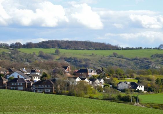 A tractor working farmland in rolling English countryside