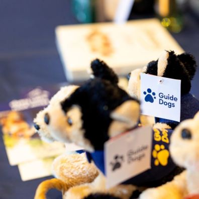 Some Guide Dogs fluffy soft toys on a merchandise stand. 