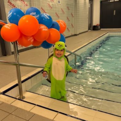 Baby in fancy dress stood by pool