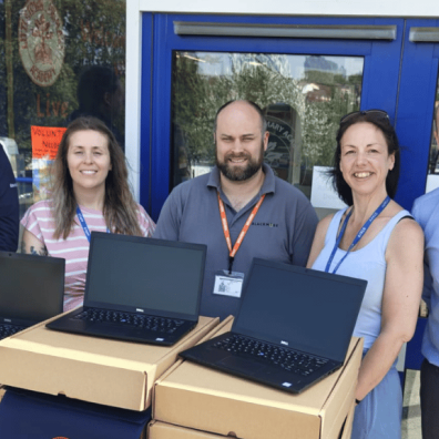Staff standing with new refurbished laptops for pupils