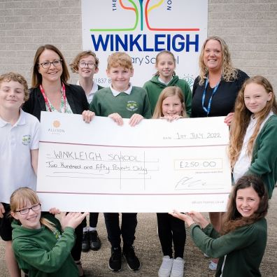 Michele Jones, Allison Homes Sales and Marketing Manager, presents a cheque for £250 to Executive Headteacher, Mrs Victoria Fenemore and Year 6 pupils at Winkleigh Primary School.