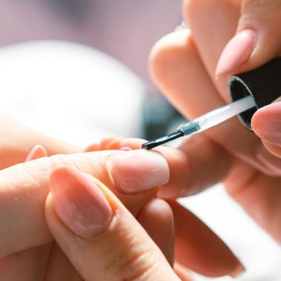Woman applying nail polish at nail salon
