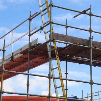 A UK tradesperson working at height with full safety equipment and scaffolding
