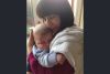 A mother lovingly cuddles her baby son with her hand cradling his head. Both have eyes closed.