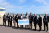 Group of people holding a large cheque on a beach
