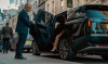Security guard holding car door open for woman
