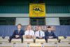 (Left to right) Toby Hard, Coby White, Fin Herbert and Jonah Shaw sit together in the stands at Torquay United Football Club, framed beneath the club’s crest. 