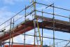 A UK tradesperson working at height with full safety equipment and scaffolding