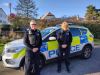 2 police officers standing beside police car